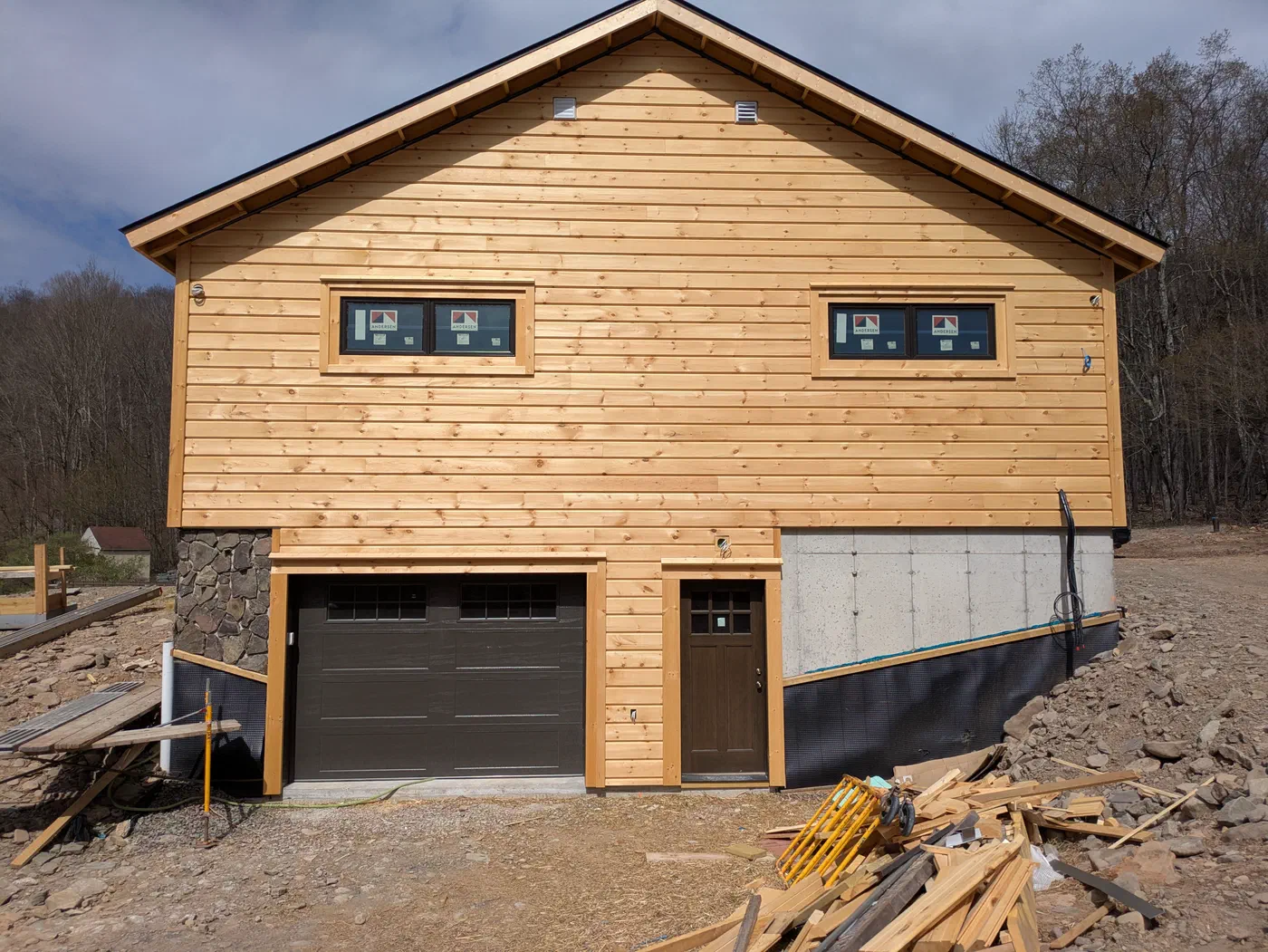 Board siding over a walkout garage with a stone corner